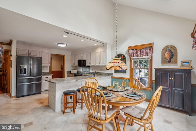 dining space with light tile patterned floors, a high ceiling, and recessed lighting