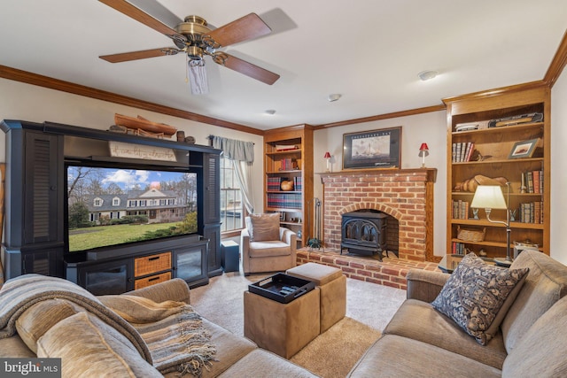 living room with ceiling fan, built in shelves, ornamental molding, carpet, and a wood stove