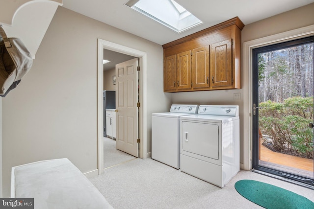 washroom with light carpet, a skylight, cabinet space, and washing machine and clothes dryer