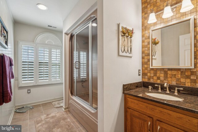 full bath with bath / shower combo with glass door, visible vents, vanity, baseboards, and tile patterned floors