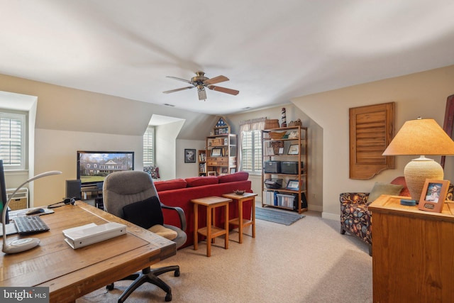 office space featuring a ceiling fan, lofted ceiling, light colored carpet, and baseboards