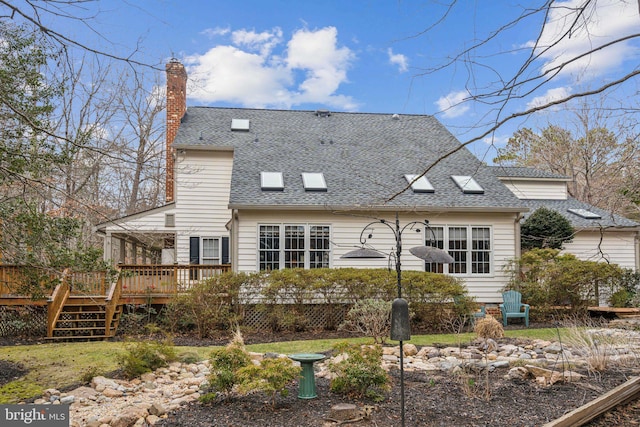 back of property featuring a chimney, roof with shingles, and a deck