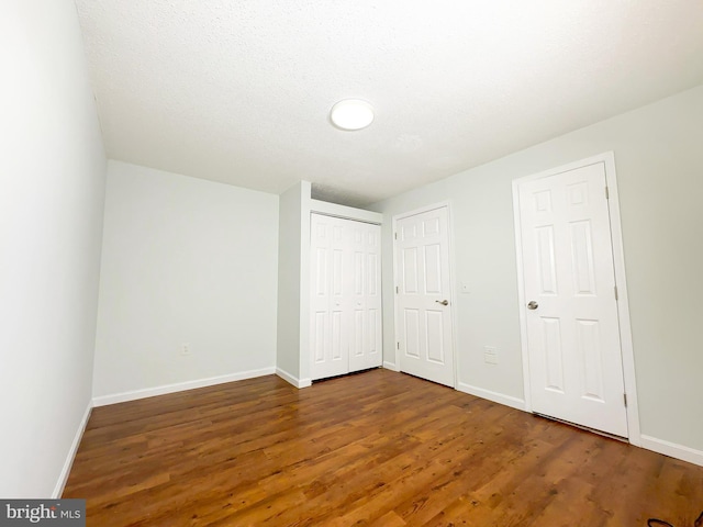 unfurnished bedroom with a closet, baseboards, and wood finished floors