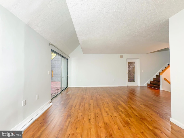 unfurnished living room featuring light wood-type flooring, a textured ceiling, baseboards, and stairs