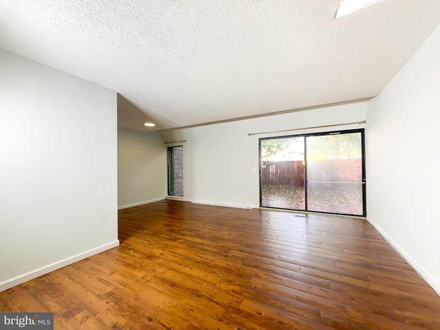 empty room featuring a textured ceiling, baseboards, and wood finished floors