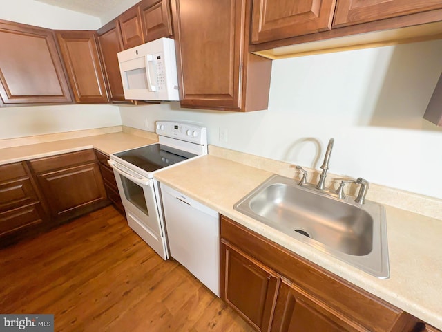 kitchen with white appliances, dark wood-type flooring, a sink, light countertops, and brown cabinetry