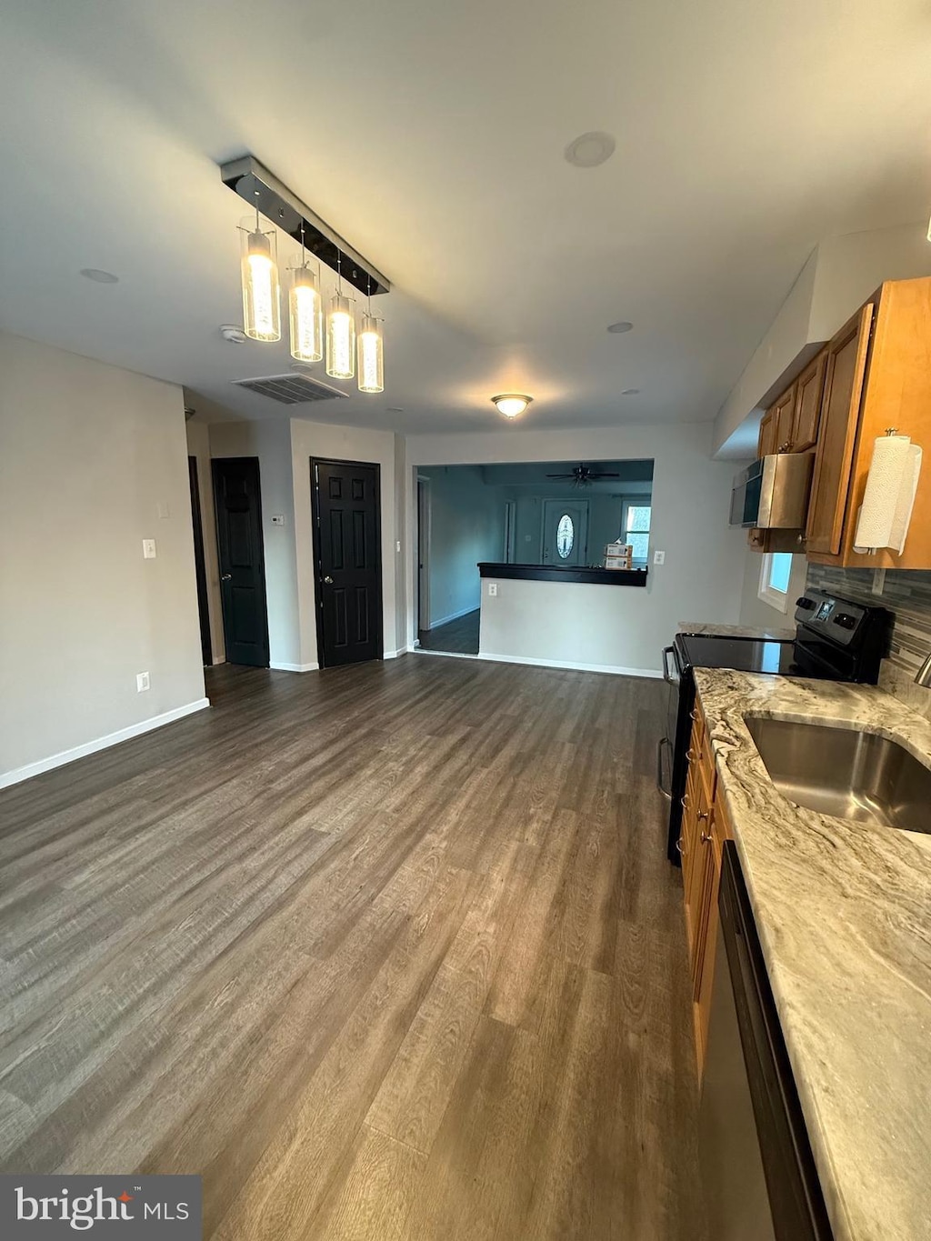 kitchen featuring open floor plan, brown cabinets, black electric range oven, dishwasher, and dark wood finished floors