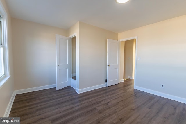 unfurnished bedroom featuring baseboards and dark wood-type flooring