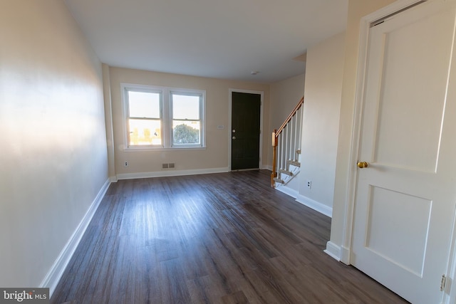 foyer with stairs, dark wood-style floors, visible vents, and baseboards