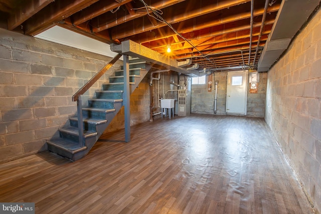 basement with stairway, a sink, and wood finished floors