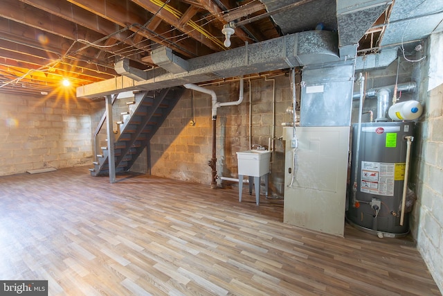 unfinished below grade area featuring a sink, water heater, stairway, and wood finished floors