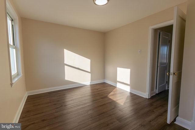 unfurnished room featuring dark wood-type flooring and baseboards