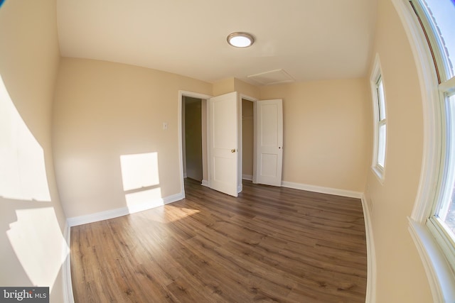 interior space featuring attic access, baseboards, and wood finished floors