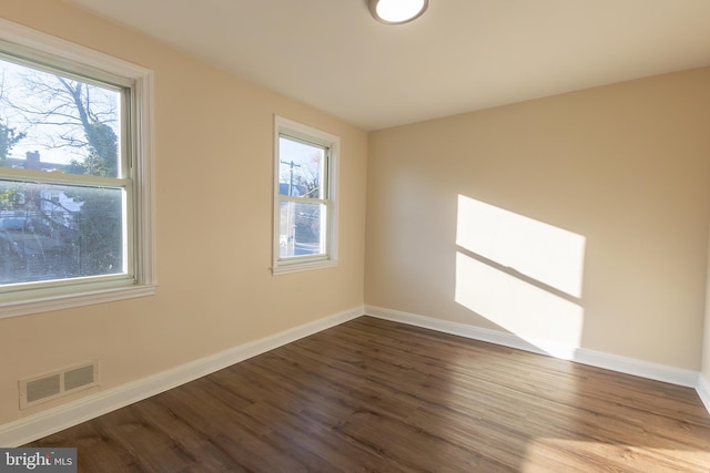 unfurnished room with wood finished floors, visible vents, and baseboards