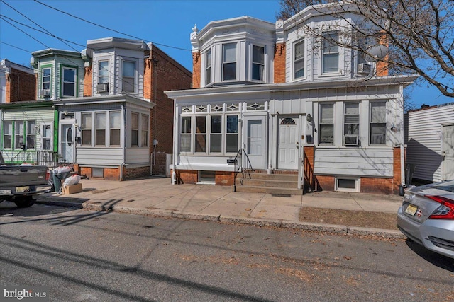 view of front of property featuring entry steps, board and batten siding, cooling unit, and a sunroom