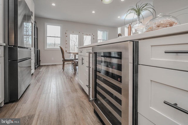 kitchen featuring wine cooler, recessed lighting, white cabinets, light wood-type flooring, and freestanding refrigerator