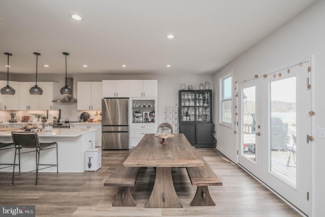 dining space with light wood finished floors, recessed lighting, and french doors