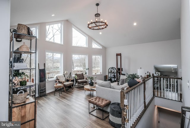 living room with high vaulted ceiling, recessed lighting, wood finished floors, and a notable chandelier