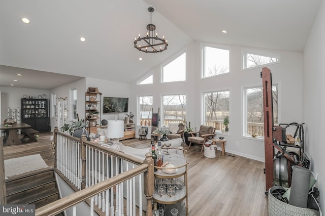 living area with an inviting chandelier, high vaulted ceiling, wood finished floors, and recessed lighting