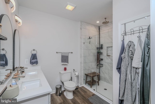 full bath with double vanity, a sink, toilet, and wood finished floors