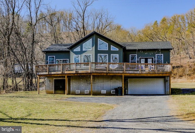 exterior space featuring a deck, a front lawn, an attached garage, and aphalt driveway