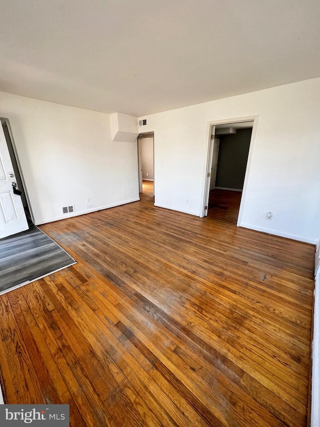 interior space featuring visible vents, dark wood-type flooring, and baseboards