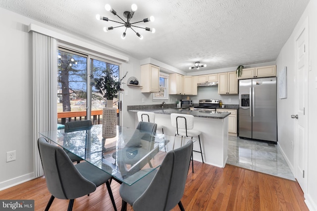 dining space with light wood-style flooring, baseboards, and a textured ceiling