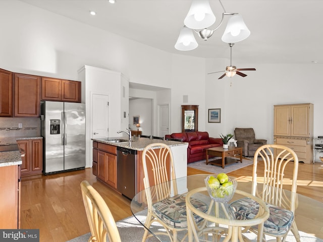 dining area with a high ceiling, light wood-style flooring, and a ceiling fan