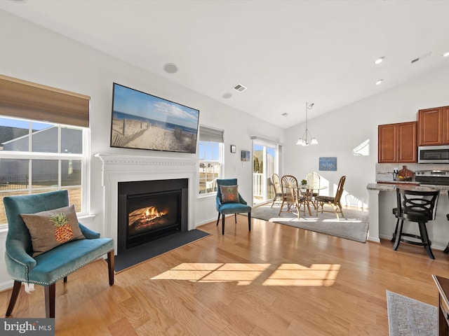 interior space featuring lofted ceiling, light wood finished floors, a fireplace with flush hearth, and visible vents