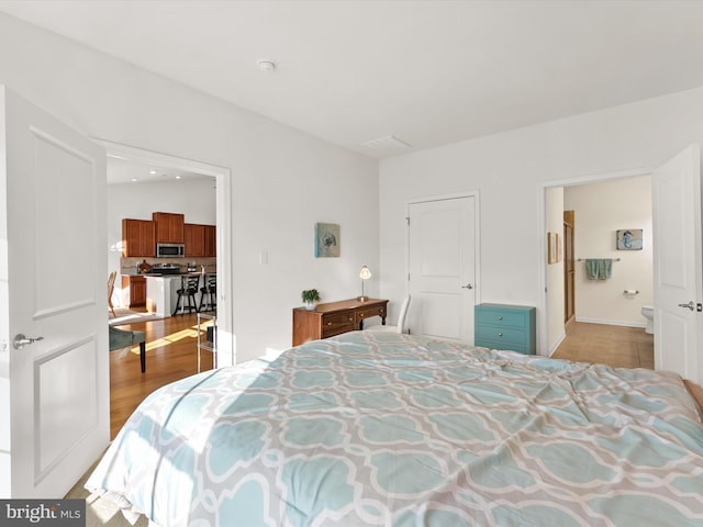 bedroom featuring wood finished floors and connected bathroom