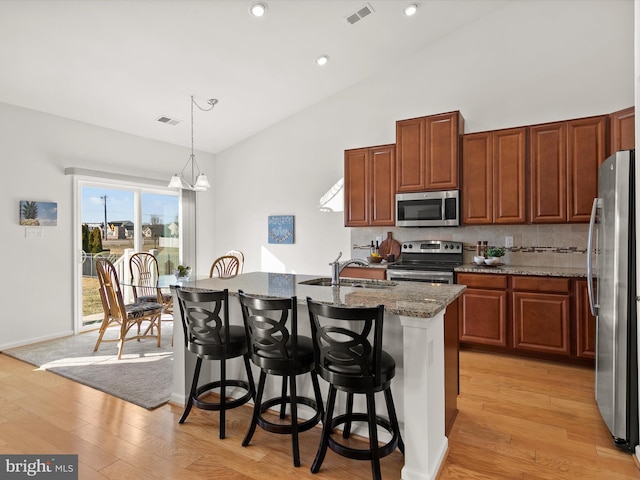 kitchen with light wood finished floors, visible vents, appliances with stainless steel finishes, a kitchen bar, and a sink