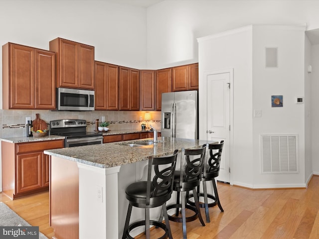 kitchen featuring stainless steel appliances, visible vents, a sink, and light stone counters