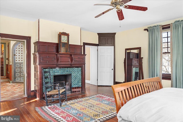 bedroom with dark wood finished floors, a tile fireplace, and baseboards