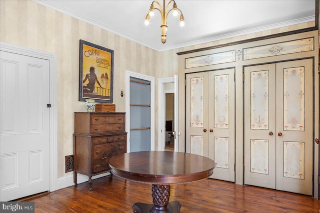 interior space with a chandelier, dark wood-style floors, crown molding, and wallpapered walls