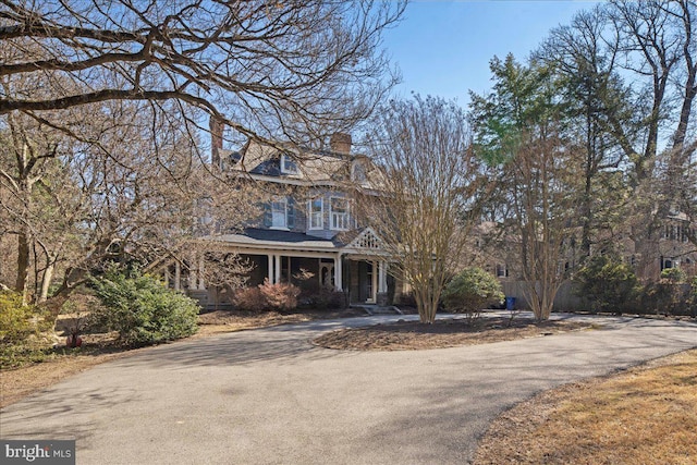 shingle-style home with a chimney and driveway