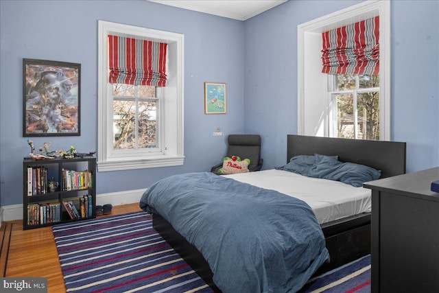 bedroom featuring multiple windows, baseboards, and wood finished floors