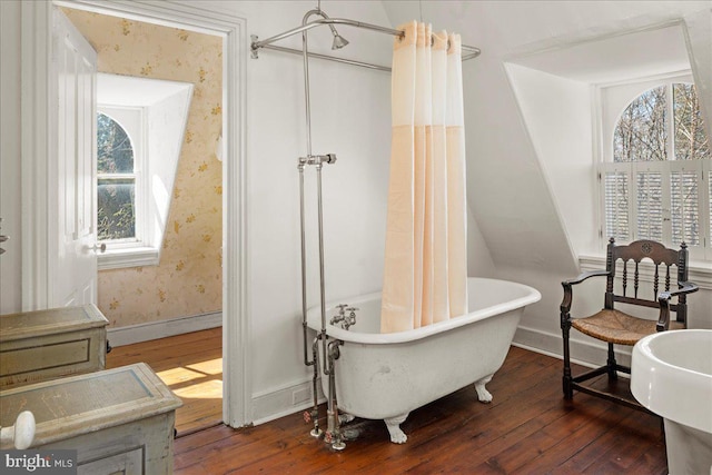 bathroom featuring hardwood / wood-style flooring, a freestanding bath, and wallpapered walls