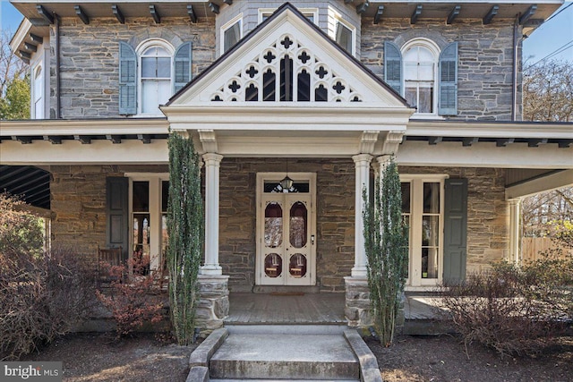 view of exterior entry featuring stone siding and covered porch