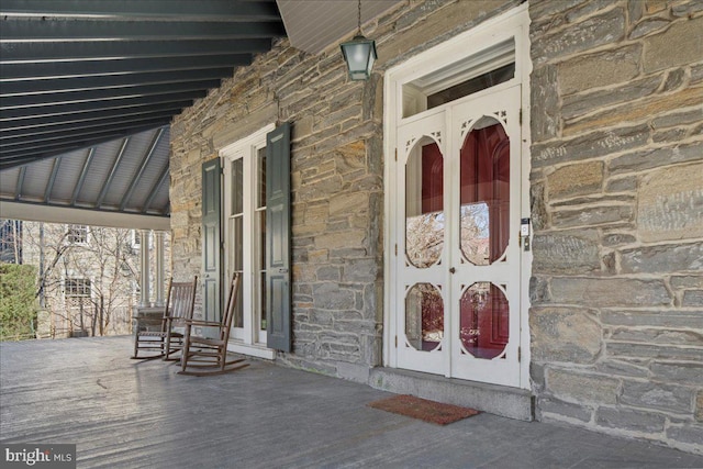 entrance to property with covered porch and stone siding