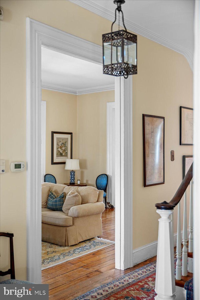 hall featuring an inviting chandelier, stairway, wood finished floors, and ornamental molding