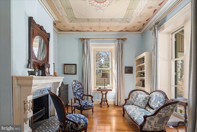 sitting room featuring a tray ceiling, wood finished floors, a fireplace, and ornamental molding