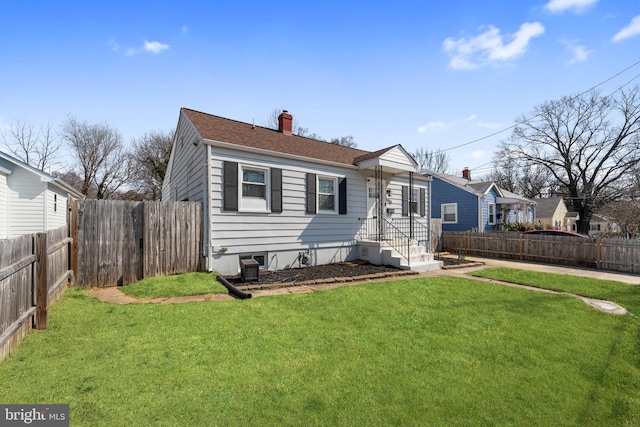 view of front facade featuring a front yard, a fenced backyard, and a chimney