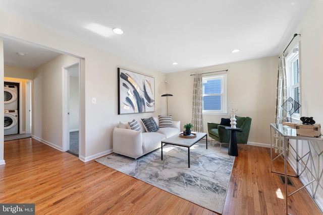 living room with stacked washing maching and dryer, plenty of natural light, and wood finished floors