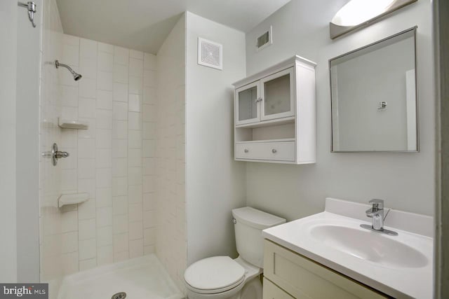 full bath featuring toilet, visible vents, a tile shower, and vanity