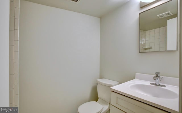 bathroom with toilet, vanity, and visible vents