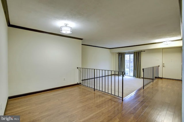 interior space with baseboards, wood finished floors, and crown molding