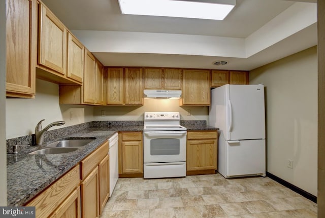 kitchen with white appliances, a sink, under cabinet range hood, and dark stone countertops