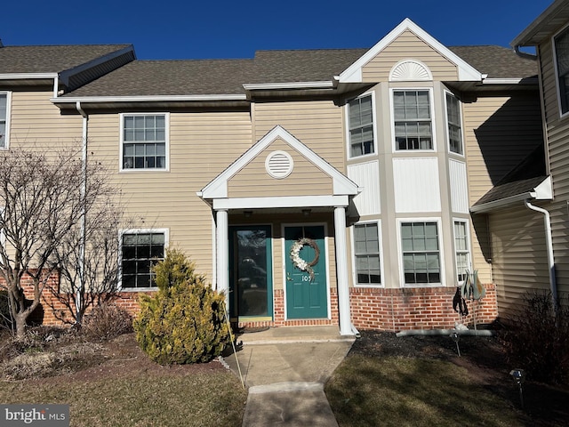 townhome / multi-family property featuring brick siding and a shingled roof