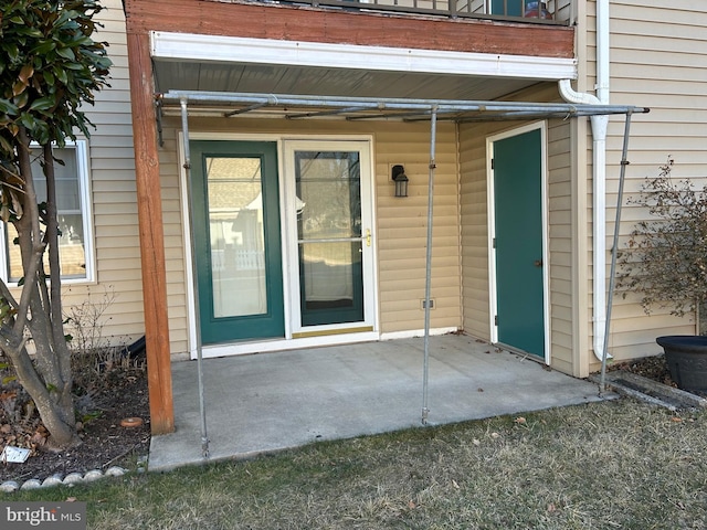 view of exterior entry featuring a patio and a balcony