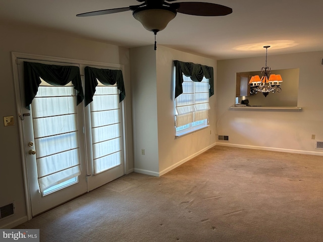 unfurnished room featuring carpet flooring, ceiling fan with notable chandelier, and visible vents